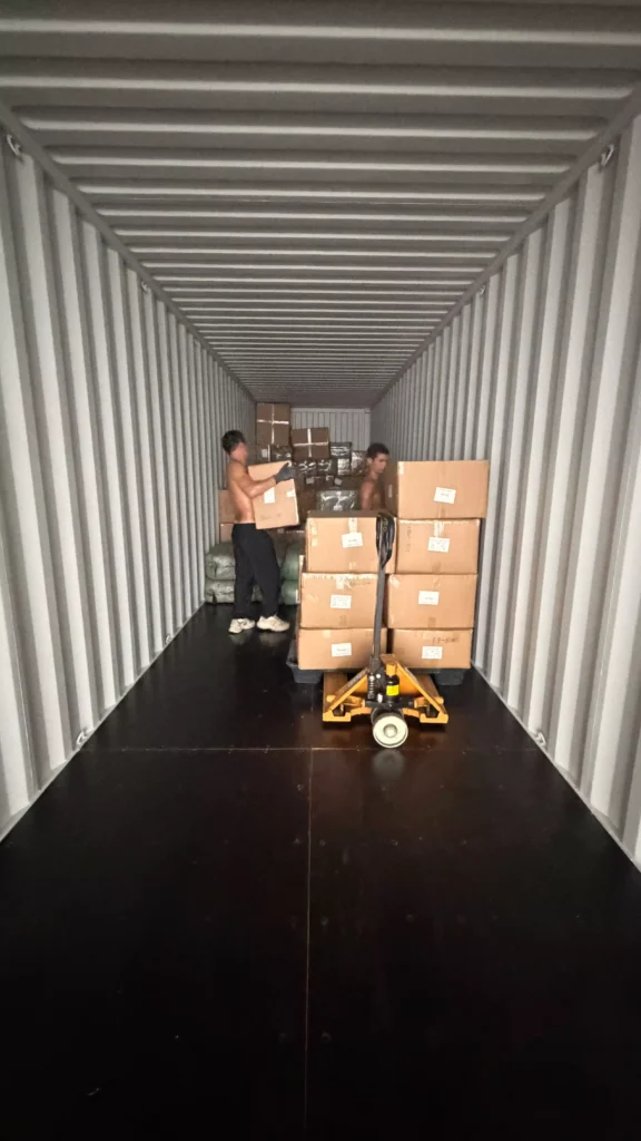 Workers manually arranging cartons during container loading