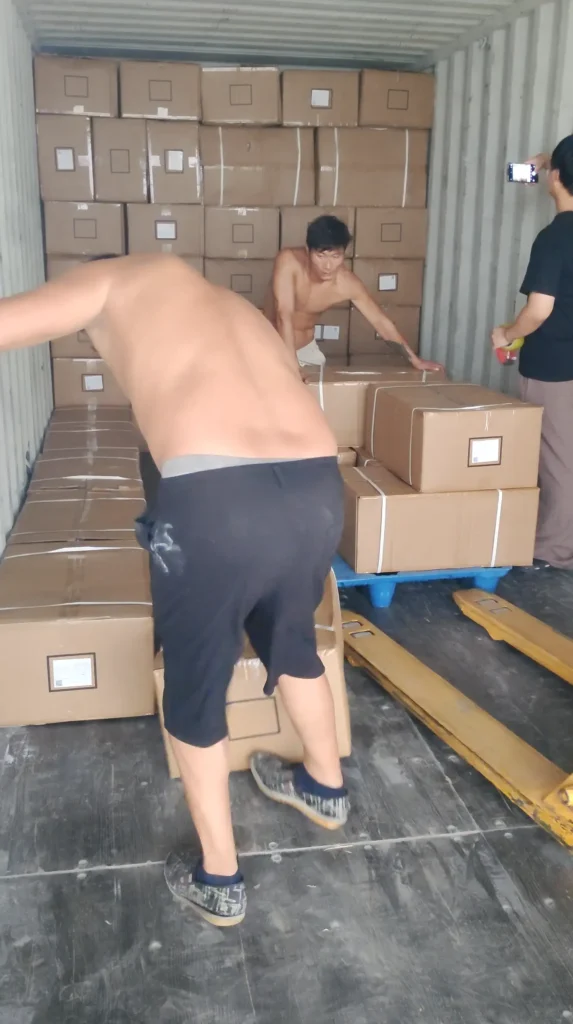 Warehouse staff planning container space after loading the first row of cartons.